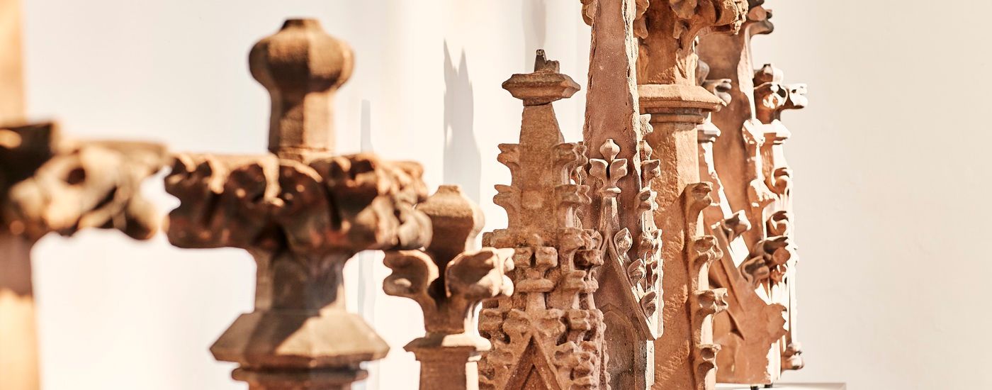 Ornate medieval stone sculptures stand upright together in an exhibition