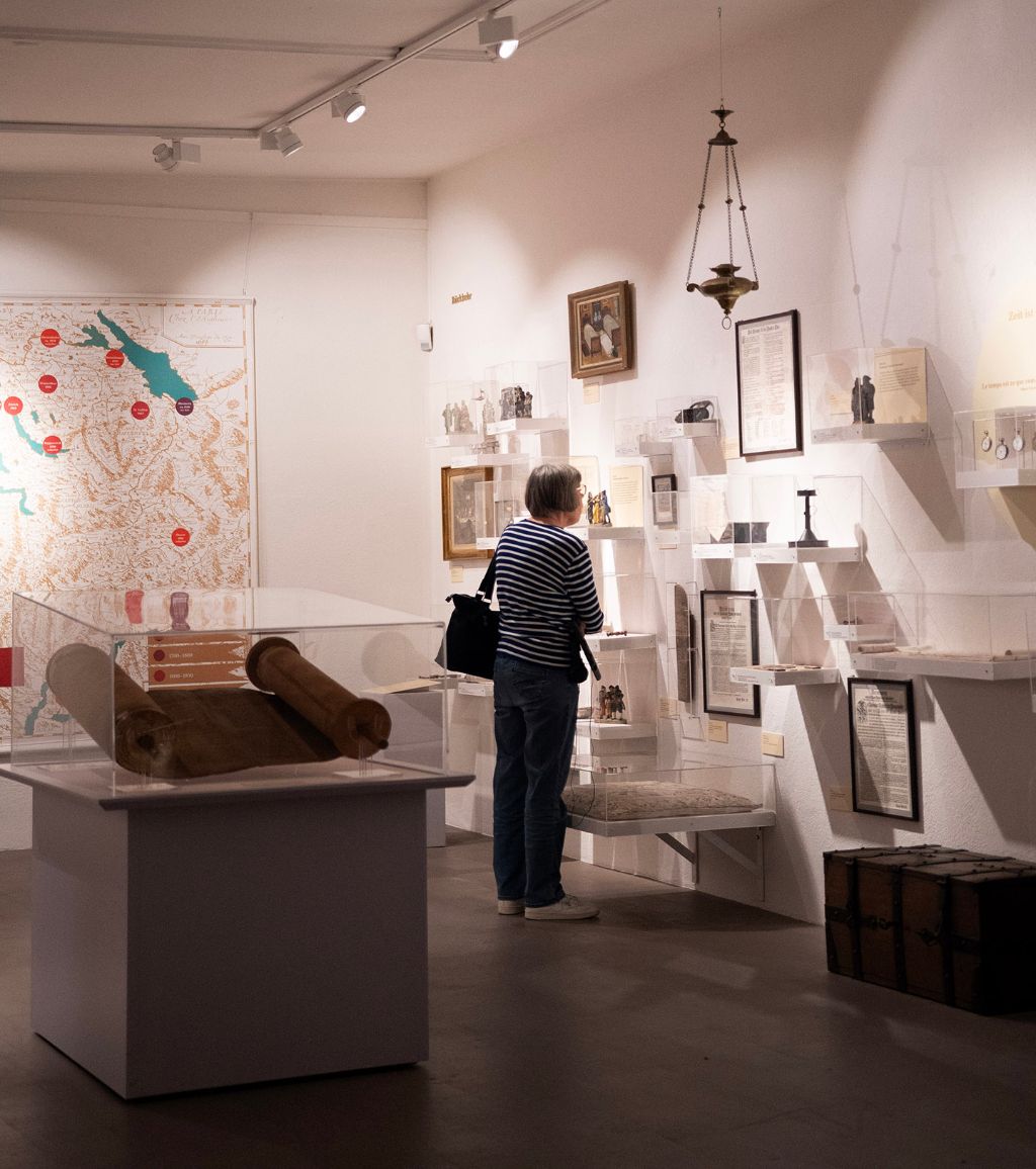A woman examines exhibits in a well-lit museum room with ancient artifacts