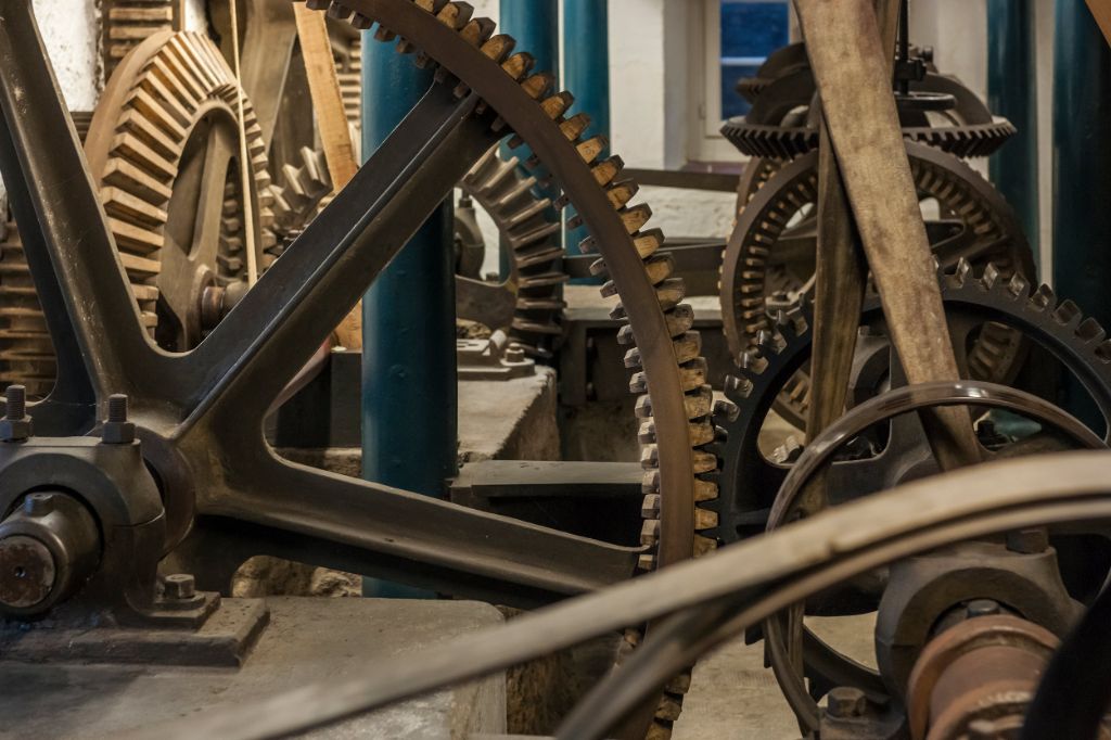Zahnräder aus Holz und Metall greifen ineinander und zeigen komplexe Mühlentechnik