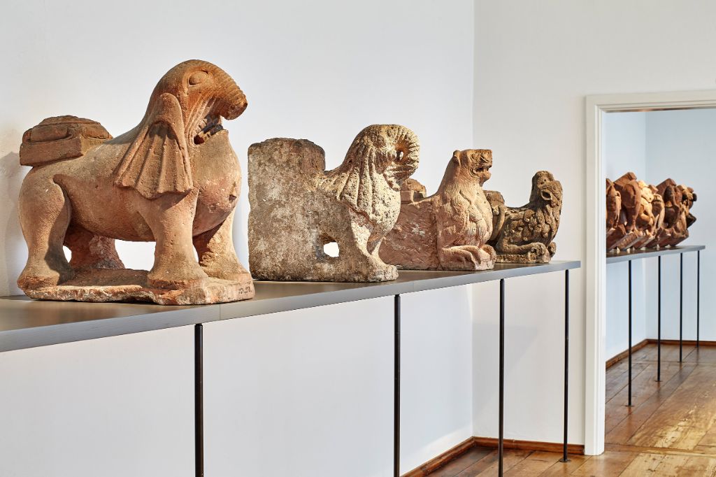 Stone lion sculptures stand on a metal table in a bright museum room