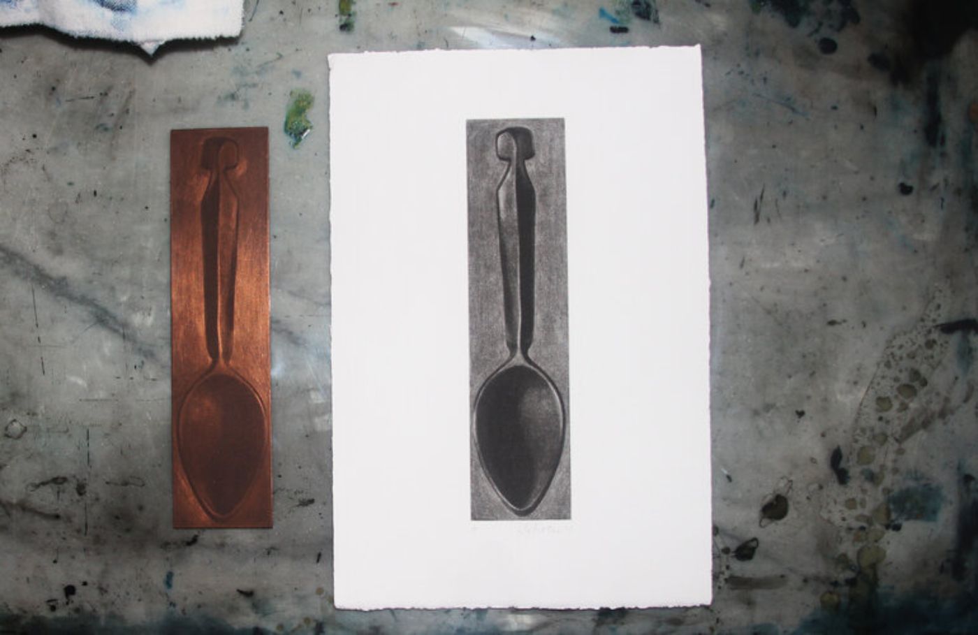 Ein Kupferstich und sein Abdruck zeigen eine minimalistische Löffelform auf grauer Oberfläche