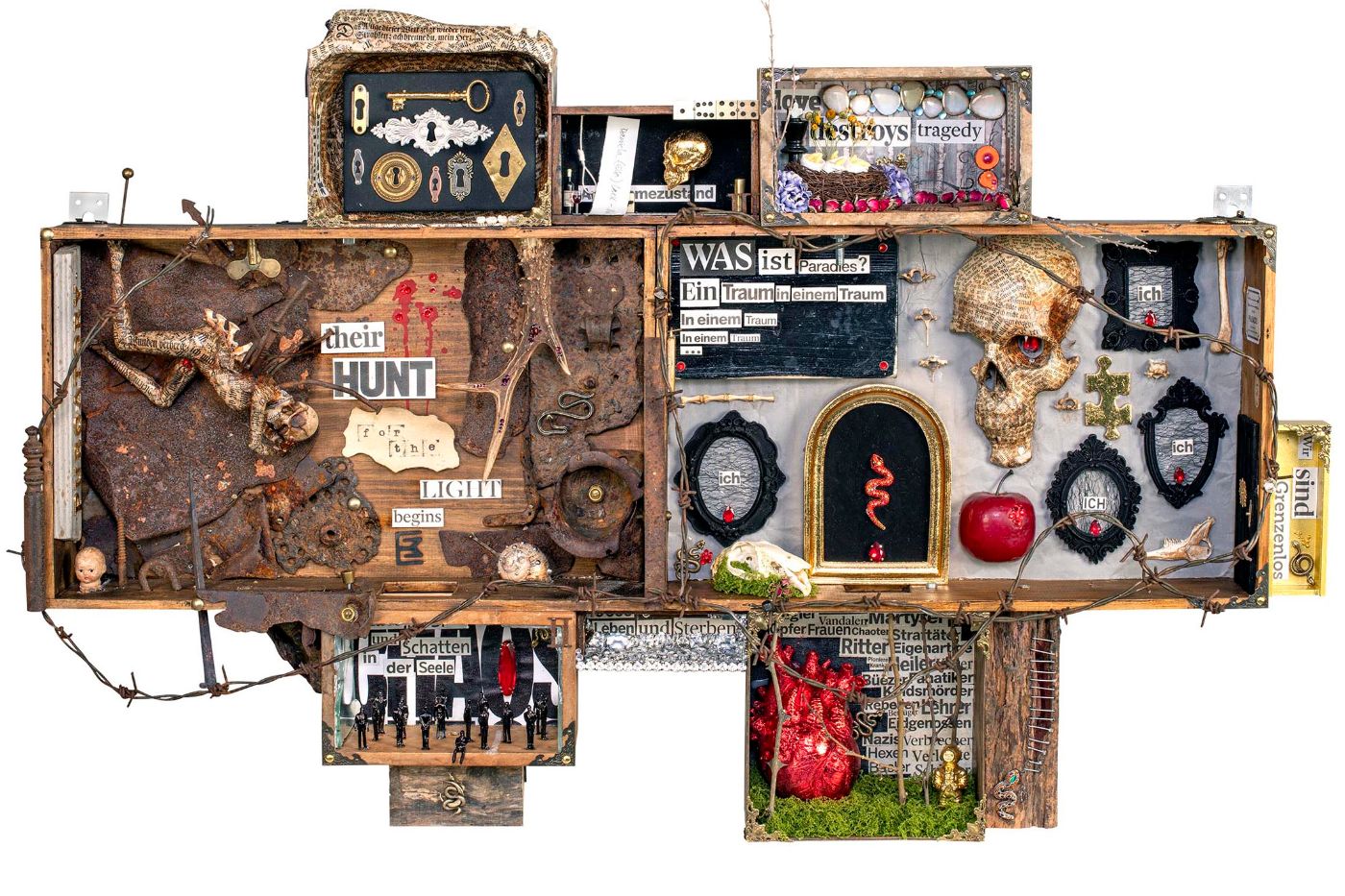 Künstlerisches Arrangement mit Skelettdarstellung, Apfel, Schädel und geschnitzten Inschriften in einem Collagerahmen.