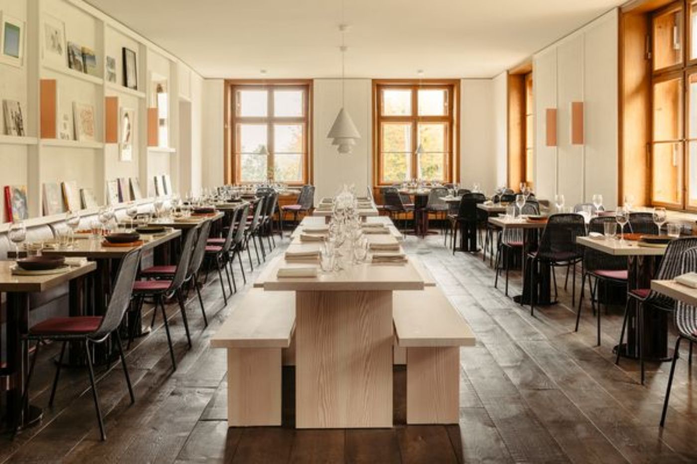 Ein elegantes Restaurant mit Holzfussboden, gedeckten Tischen und grossen Fenstern
