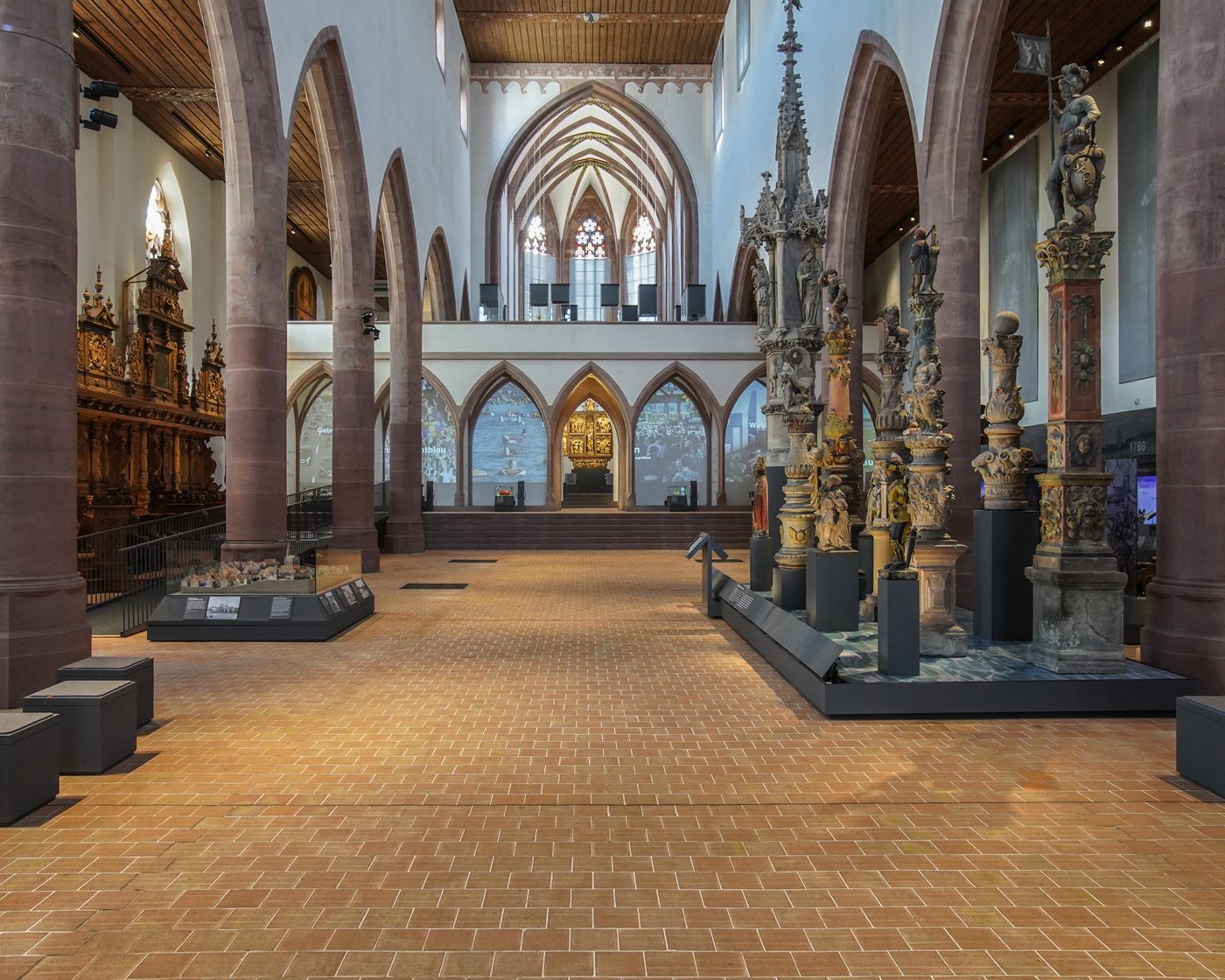 Historisches Gebäude mit großen gotischen Fenstern und beleuchteten Eingangsbereich am Abend.