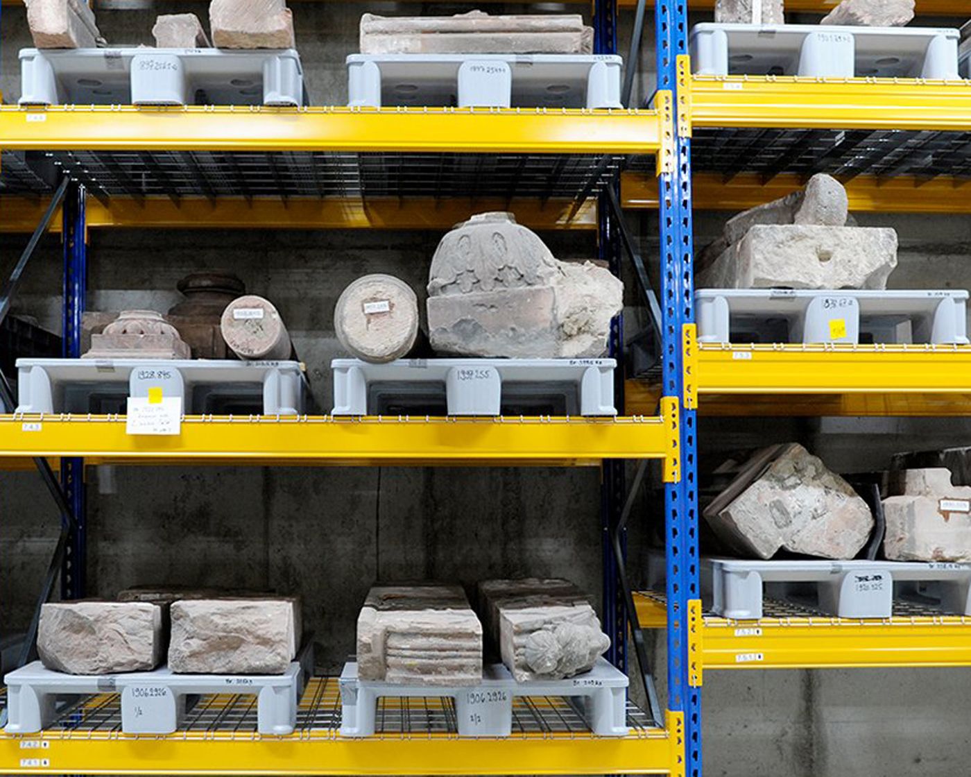 Ein Mann mit roter Mütze arbeitet sorgfältig an archäologischen Funden mit einem Pinsel.