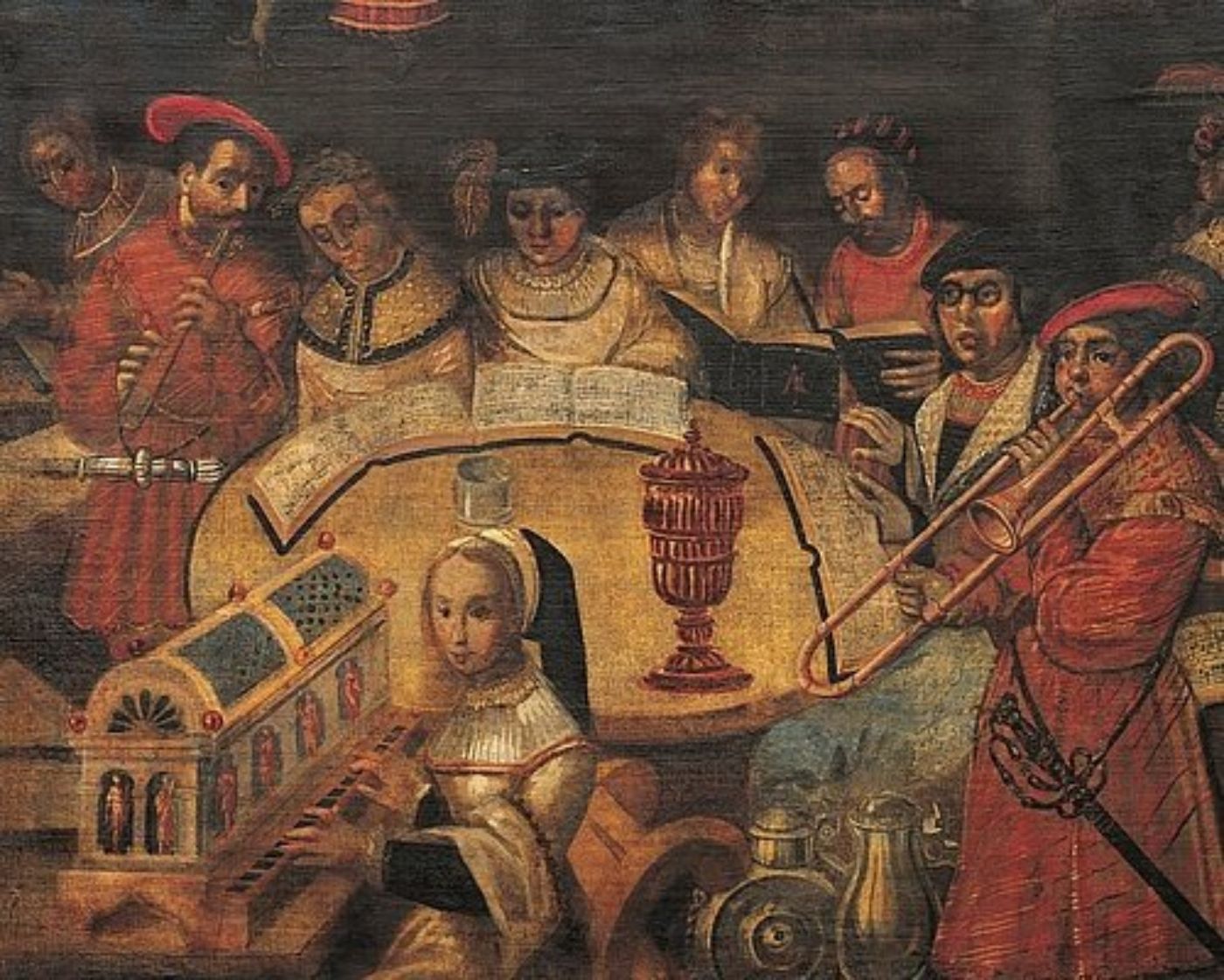 Eine Gruppe von Musikern spielt in opulenten Kostümen an einem historischen Tisch Musik.