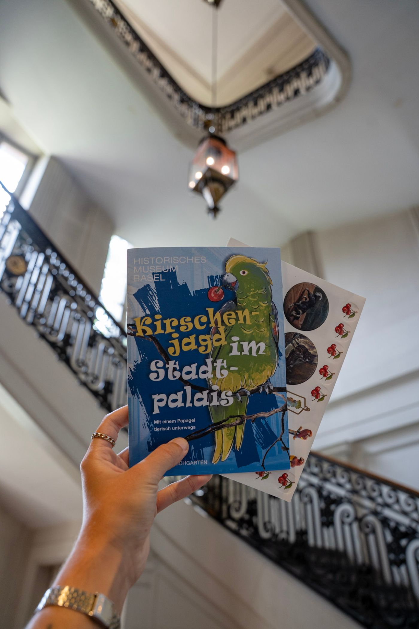 Eine geschwungene Holztreppe mit kunstvoll verziertem Eisen-Geländer im halb dunklen Licht