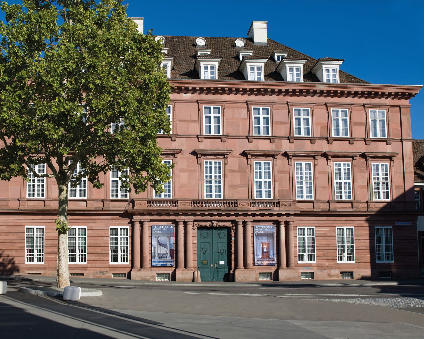 Eine geschwungene Holztreppe mit kunstvoll verziertem Eisen-Geländer im halb dunklen Licht