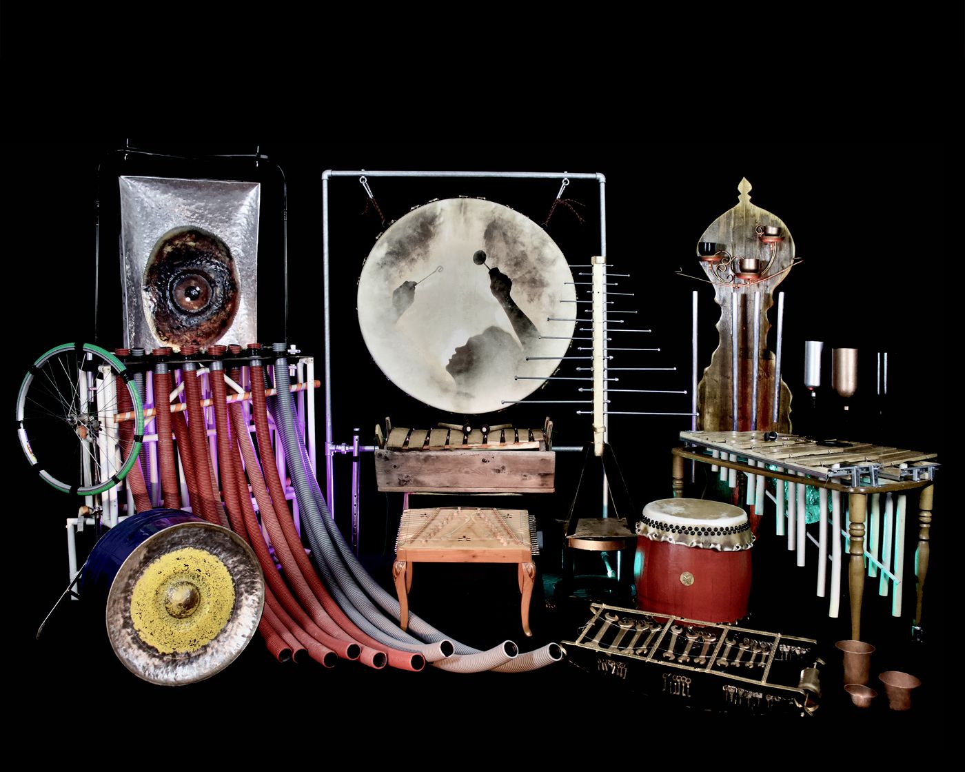 Kunstvolle Anordnung von Instrumenten aus recycelten Materialien vor schwarzem Hintergrund.
