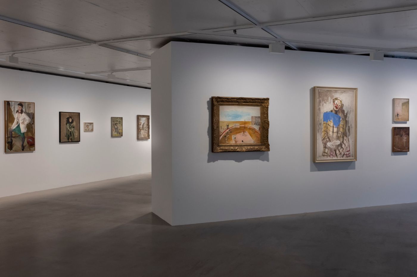 In einem modernen Ausstellungsraum hängen diverse Gemälde an weissen Wänden.