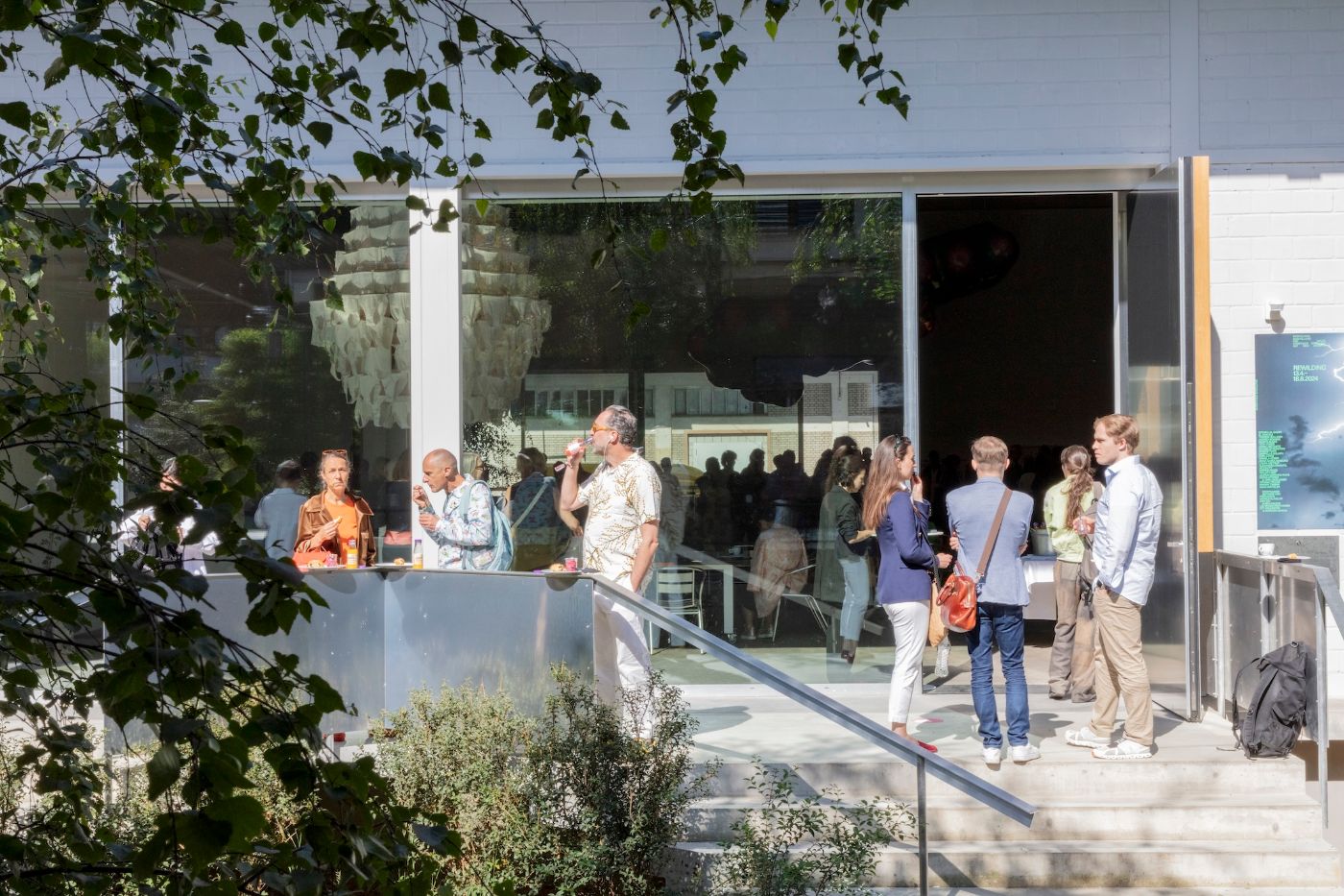 Auf einer Sonnenterrasse stehen Menschen beisammen, geniessen Getränke und unterhalten sich