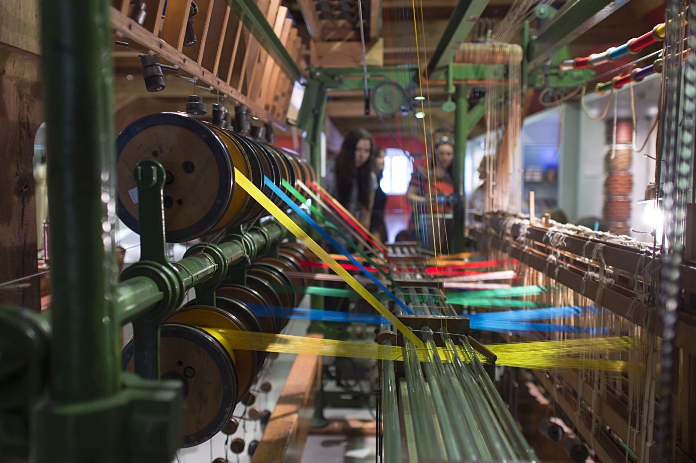 Am Sägerwebstuhl zeigt die Weberin wie Seidenbänder gewoben werden