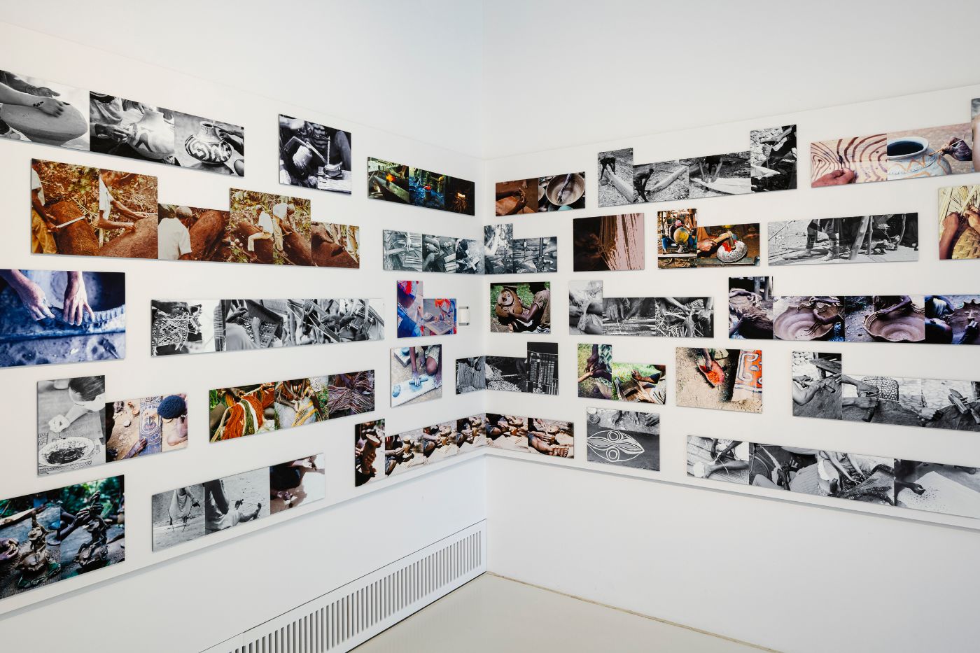 Viele Fotos von Händen hängen an einer weissen Wand.