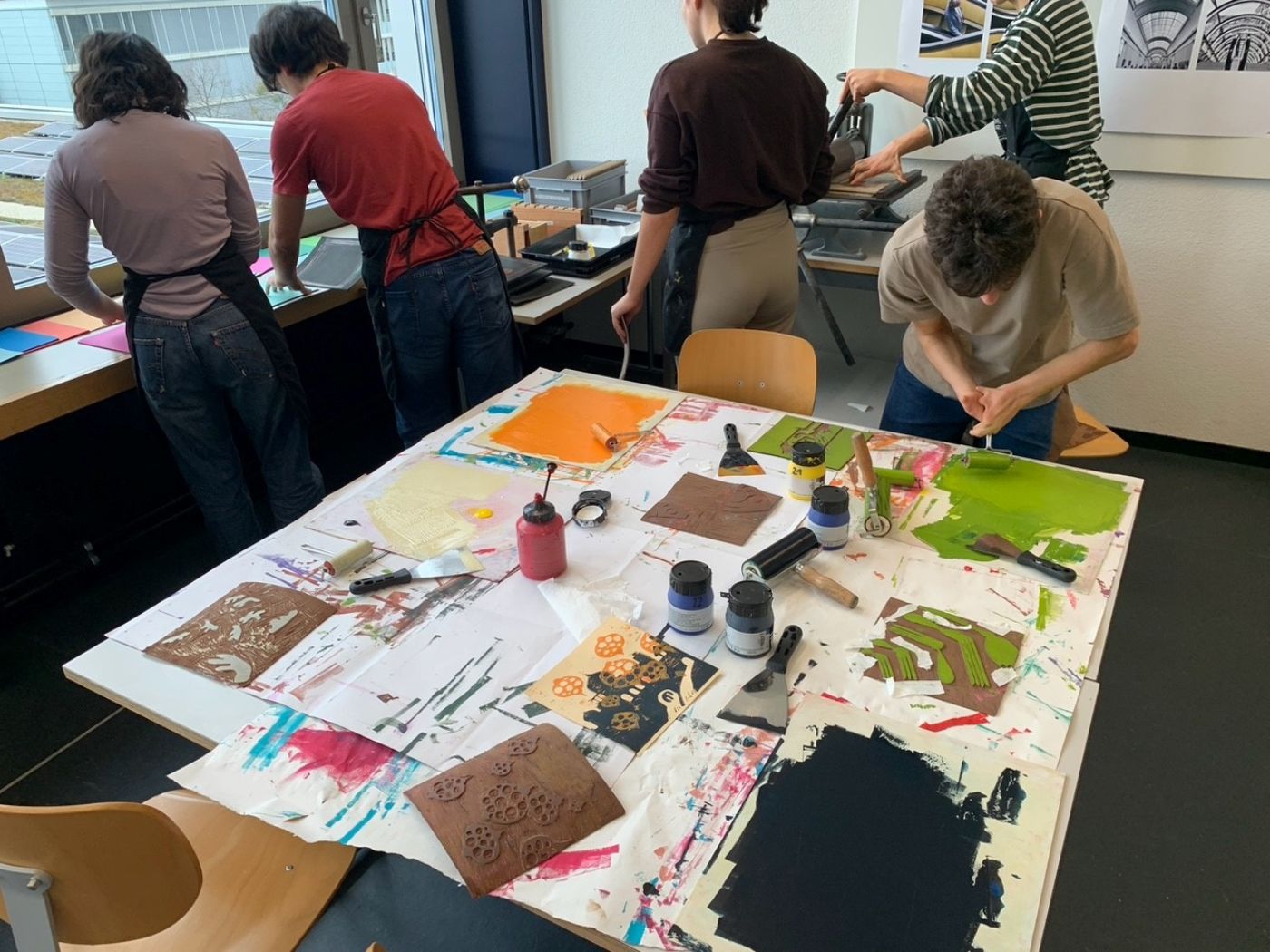 Des matériaux artistiques colorés et des outils sont sur une table tandis que quatre personnes créent