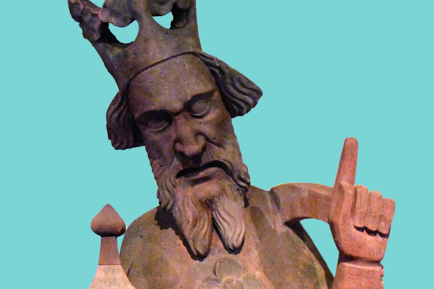 Auf dem Bild ist eine alte Skulptur eines Königs mit Bart und Krone zu sehen, der nachdenklich schaut.