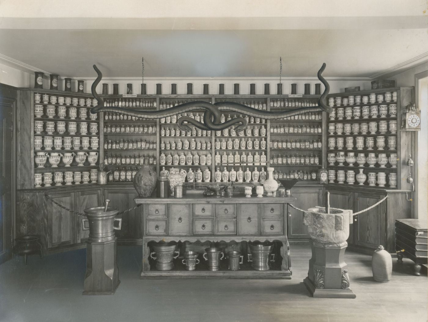 Picture of the old exhibition in the Pharmacy Museum, black/white fotography, displaying antique furniture and vessels of pharmacies