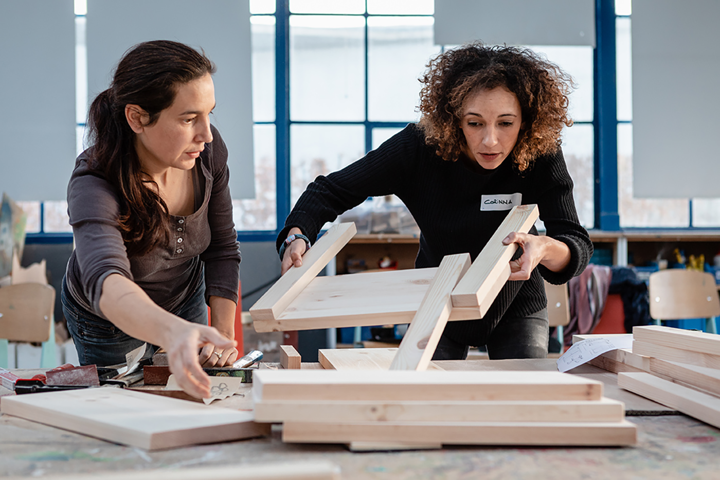 Deux femmes assemblent ensemble une chaise en bois dans un atelier